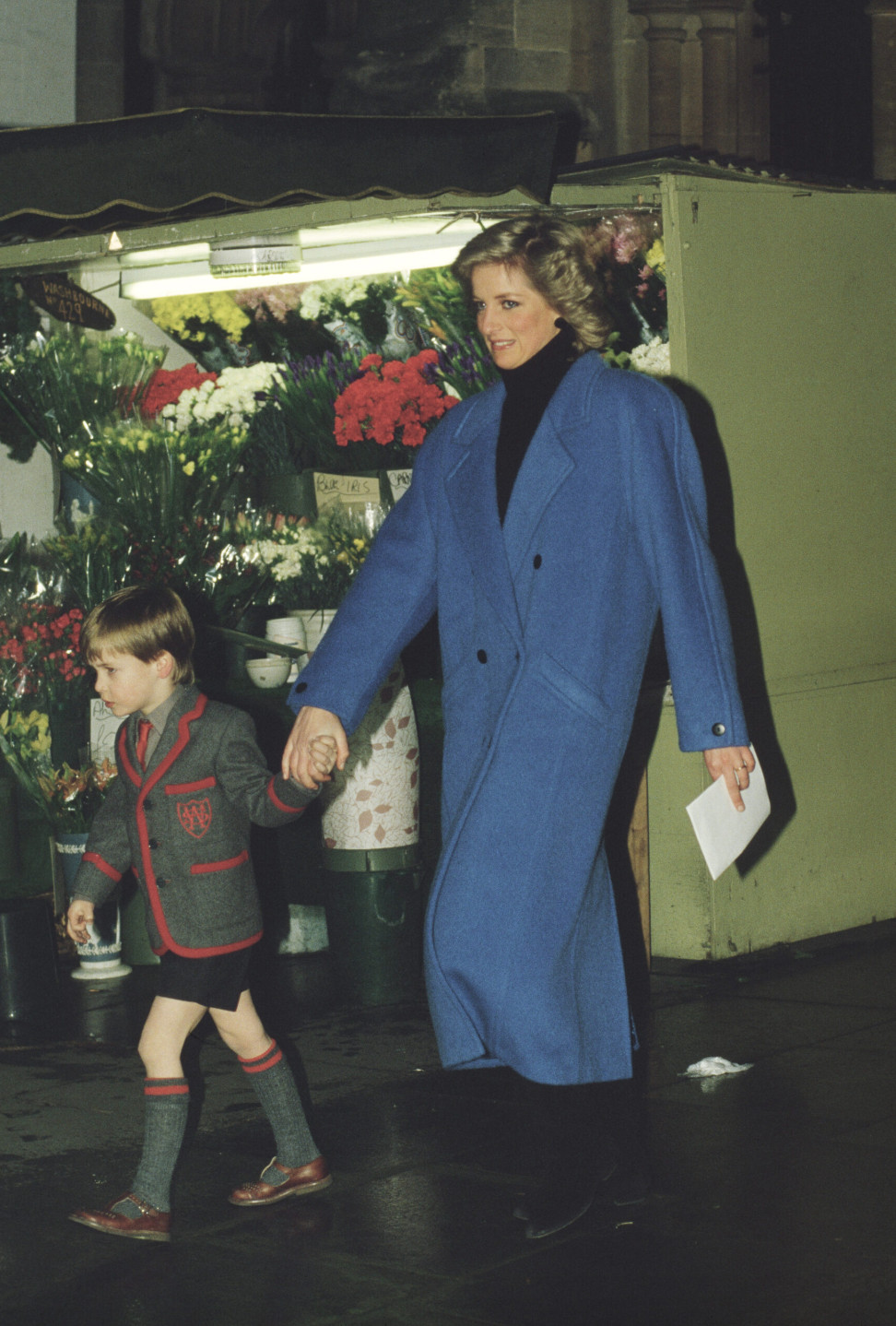 Diana, Princess of Wales and Prince William walking in London. She wears a blue overcoat over a black turtleneck sweater (Photo: Getty Images)