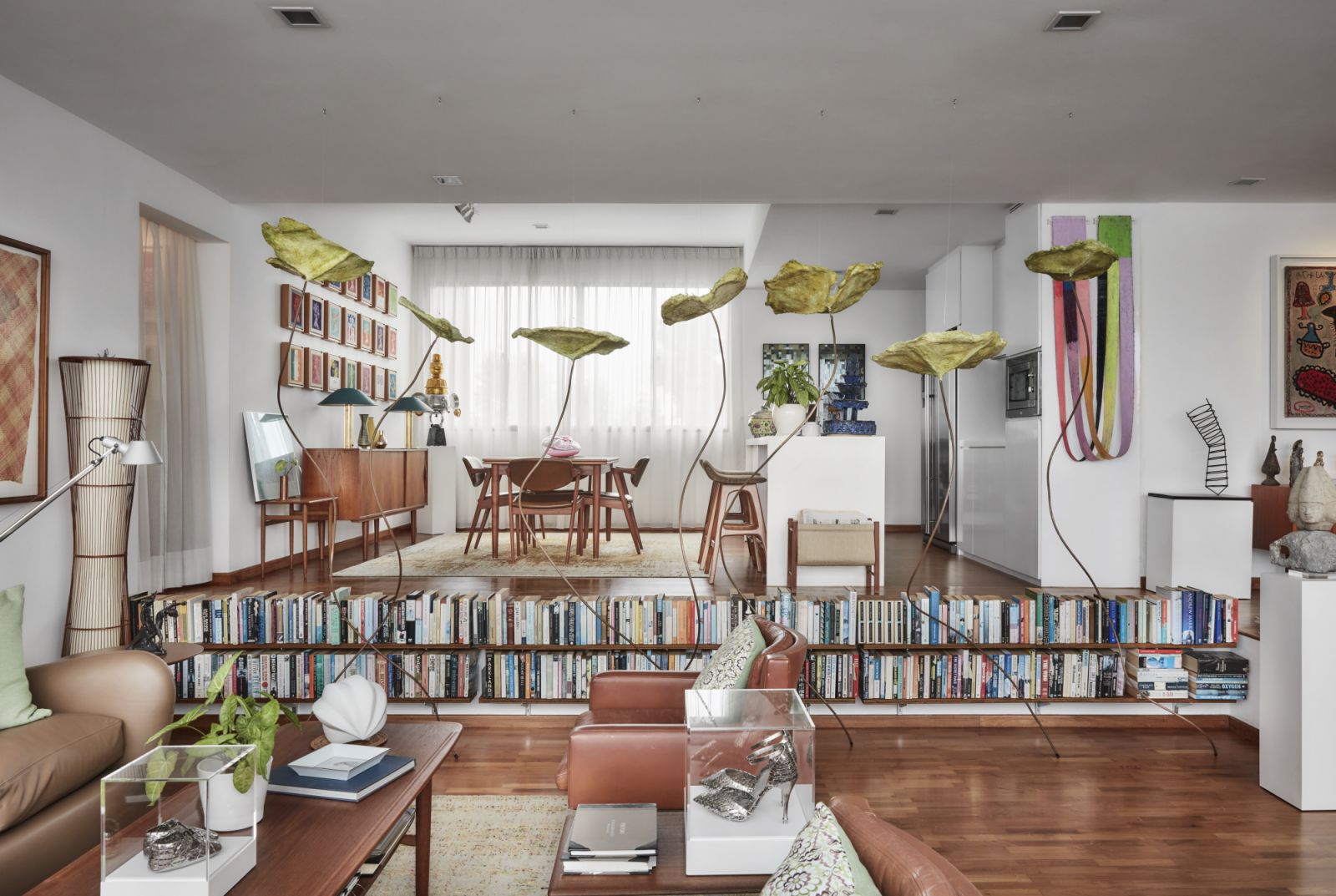 The sunken living room is partitioned off from the dining area with a low bookshelf that Budden built himself and a row of floating papier mache lotus leaves by Cambodian artist Eng Rithchandaneth, which Lyon had encountered at Jendela Visual Arts Space