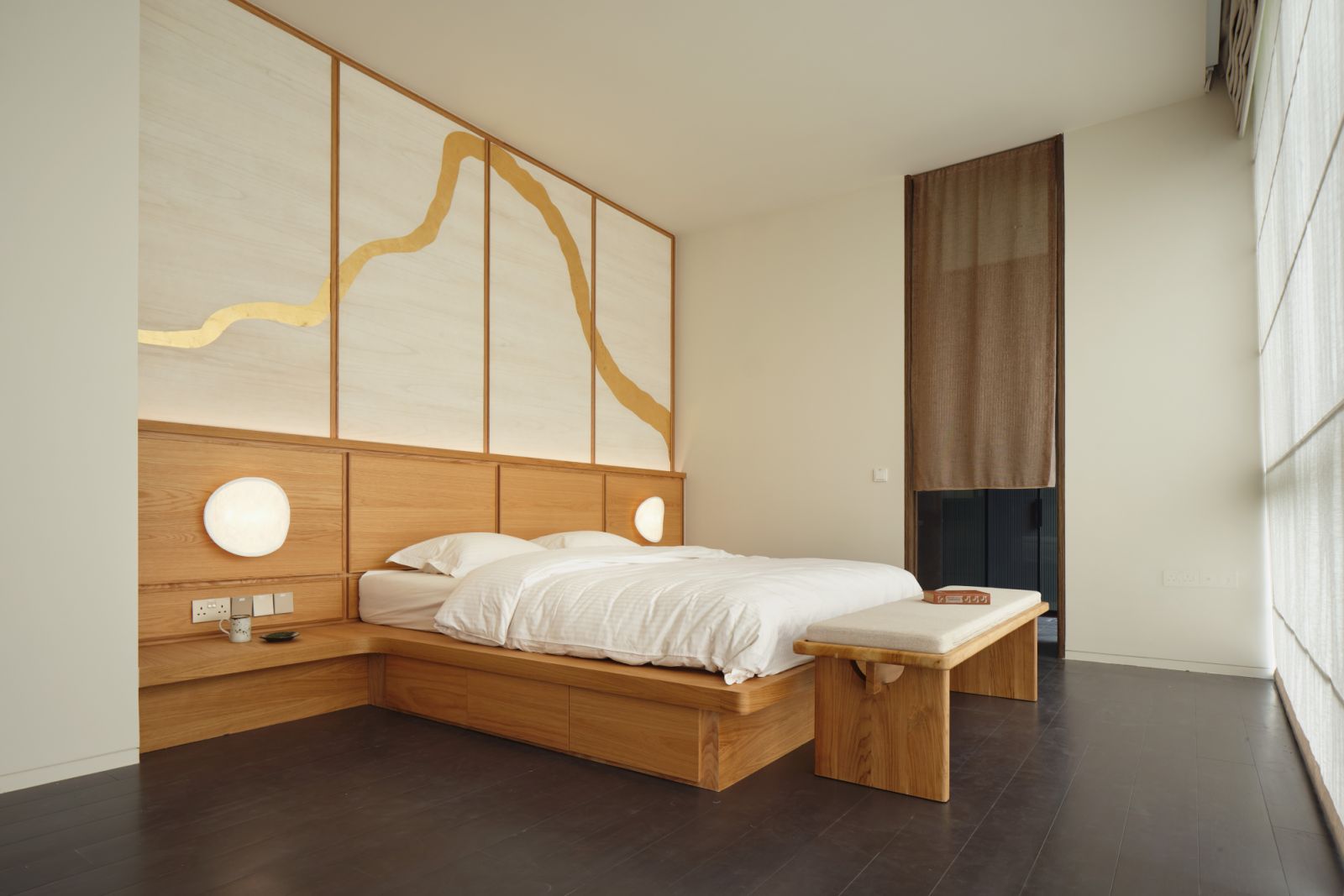 The bedroom features a platform bed with storage, a bench with traditional Chinese joinery details, handmade gold foil wallpaper and a pair of New Works Tense wall lamps from Made & Make