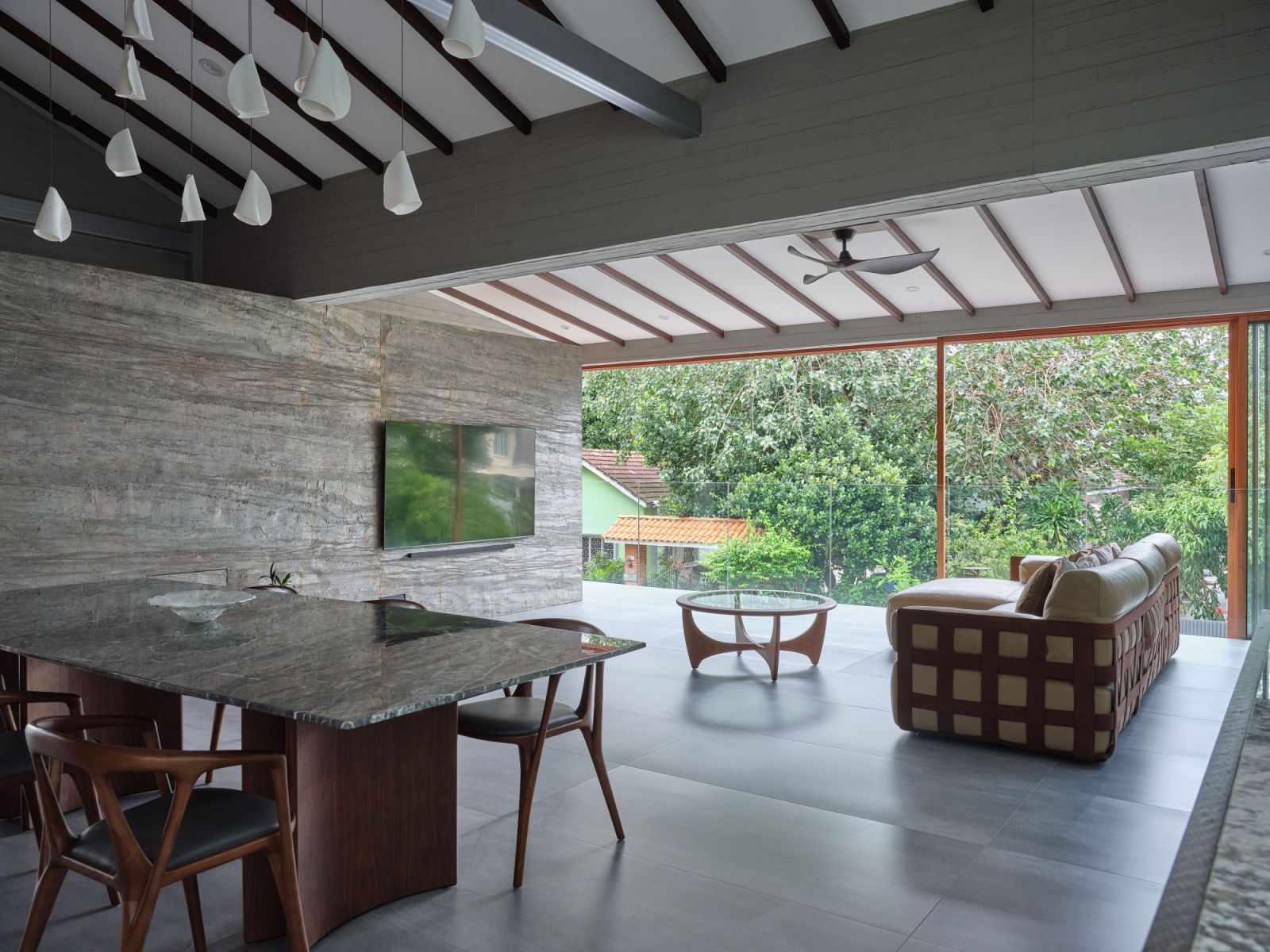 The home’s spacious living area is bathed in natural light thanks to the blending of indoor and outdoor spaces, an effect further enhanced by the use of natural materials such as stone and wood