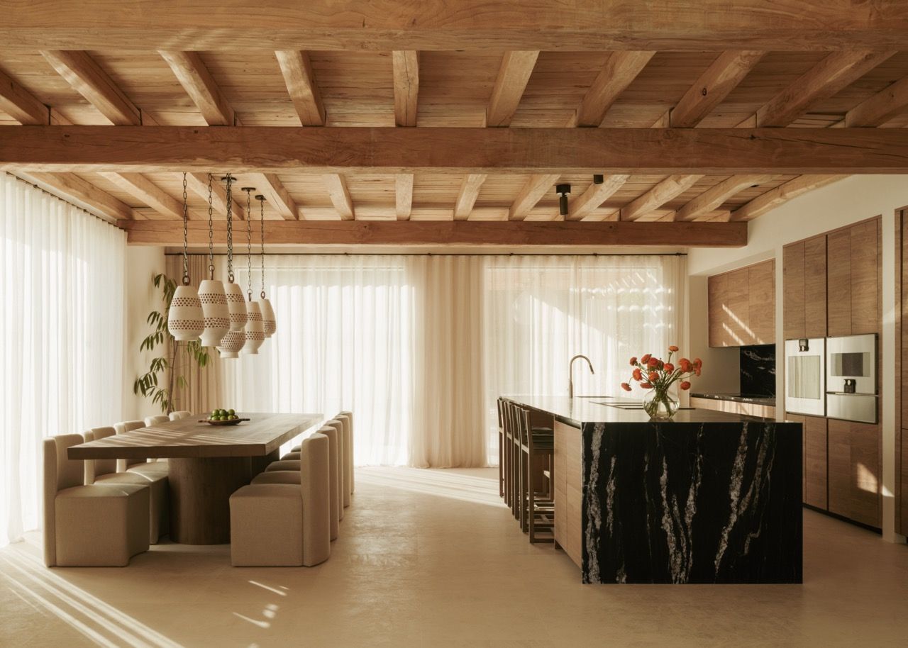 The open-plan kitchen and dining area showcase the dramatic contrast between the black marble island and warm wooden cabinetry, all unified under the traditional exposed beam ceiling structure