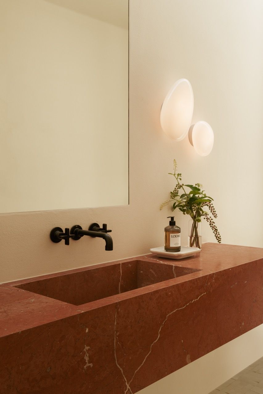 A powder room features Rojo Alicante stone—traditional to the region—combined with contemporary lighting and black fixtures for a sophisticated contrast