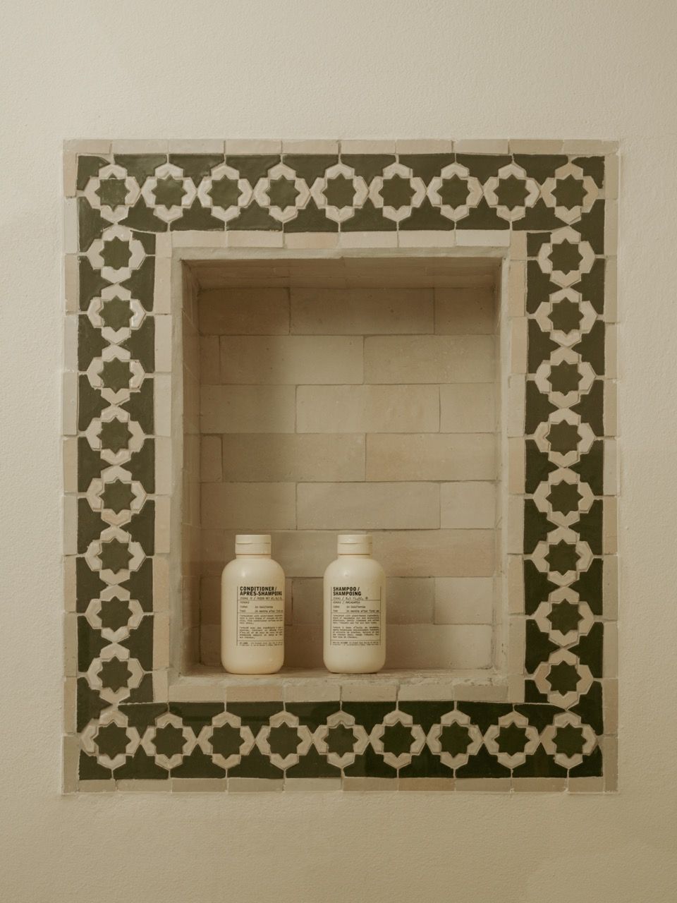 A traditional zellige tile niche provides both decorative interest and practical storage, showing how historical elements can be reinterpreted for modern use