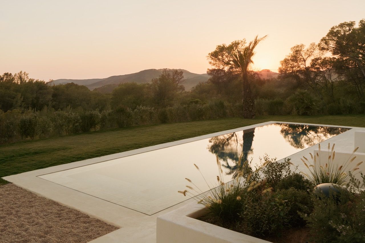 The swimming pool area exemplifies the seamless indoor-outdoor living philosophy, with the Ibiza countryside providing a dramatic backdrop for relaxation