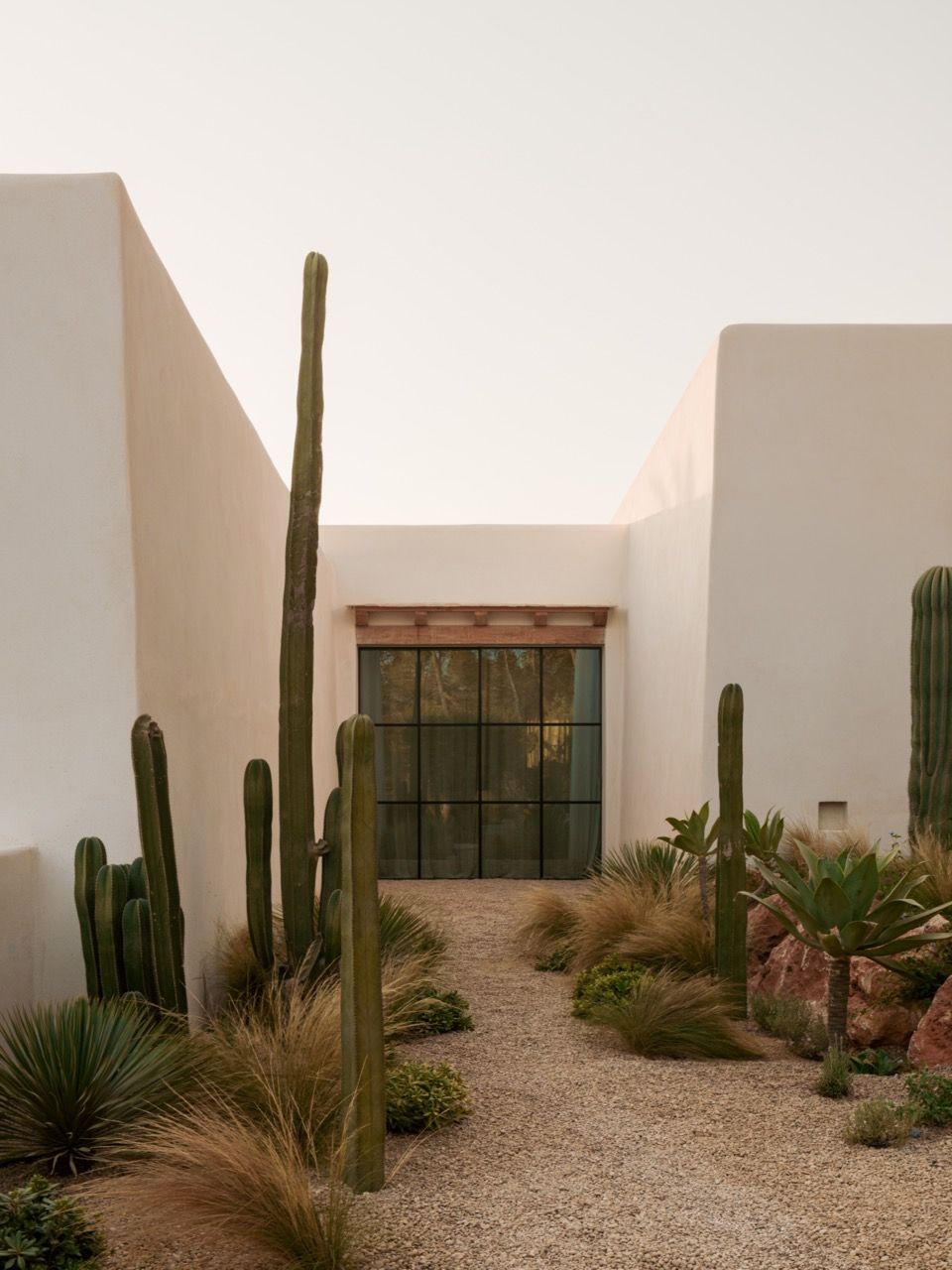 Contemporary landscaping with sculptural cacti and native plantings frames the house’s clean geometric forms whilst respecting the island’s natural character
