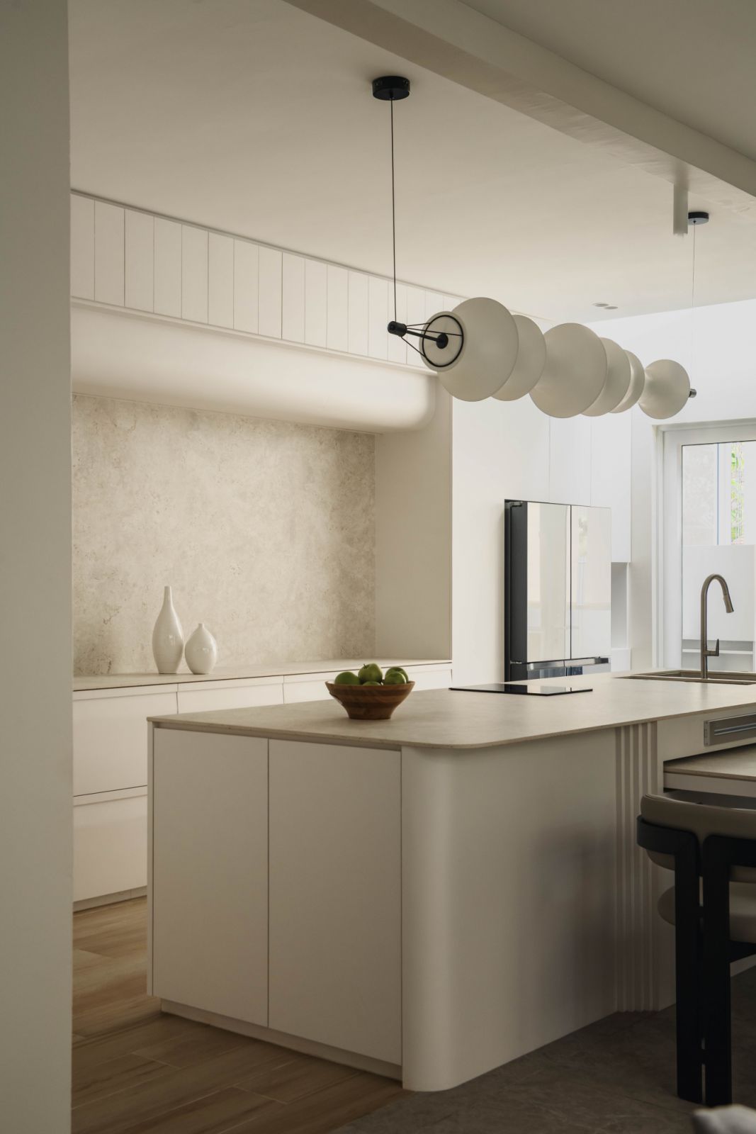 Kitchen featuring the sculptural pendant lighting and custom cabinetry that extends the natural veneer palette throughout different areas of the home