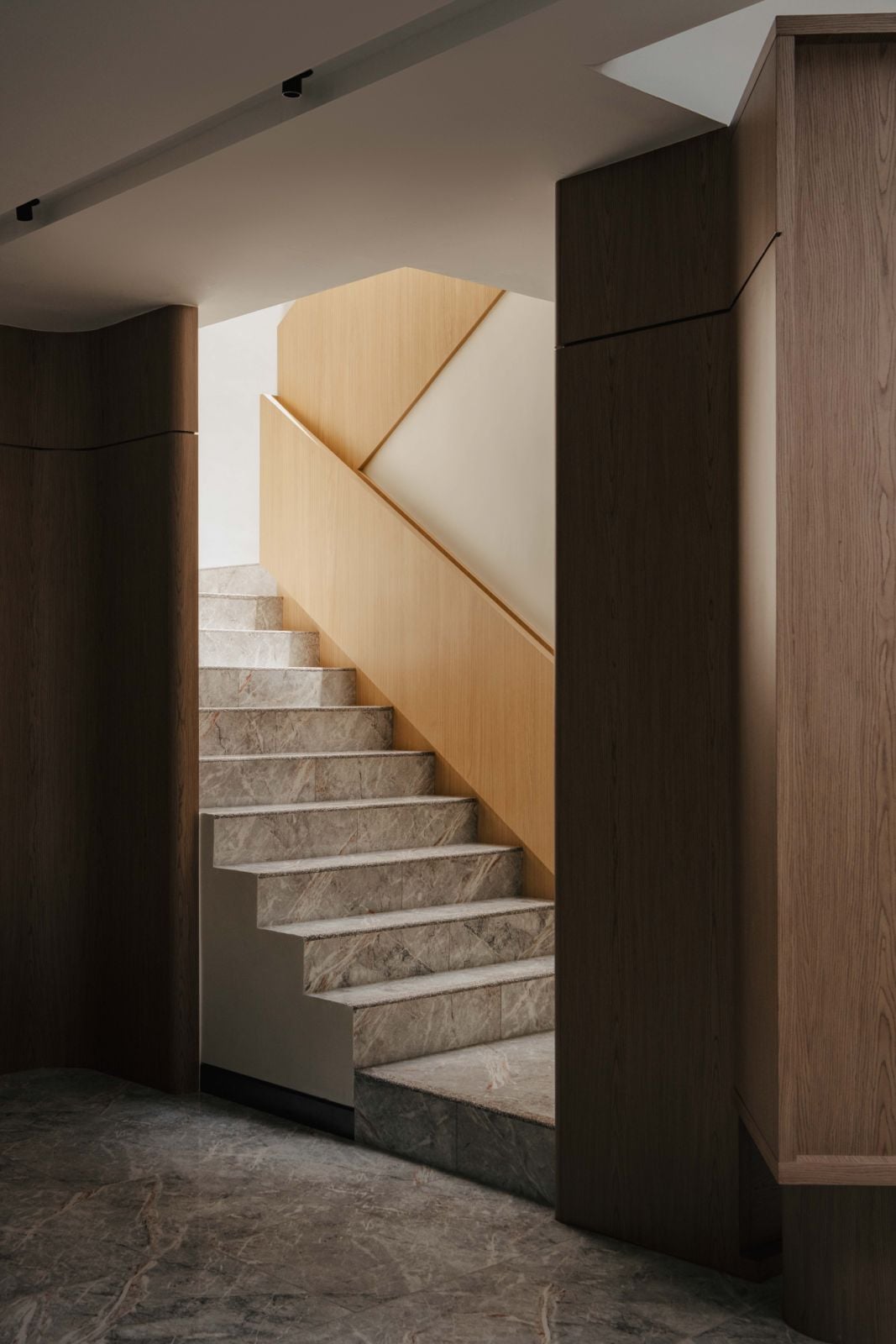 Staircase detail with natural wood and stone finishes, part of the architectural intervention that brings natural light through the double-volume void
