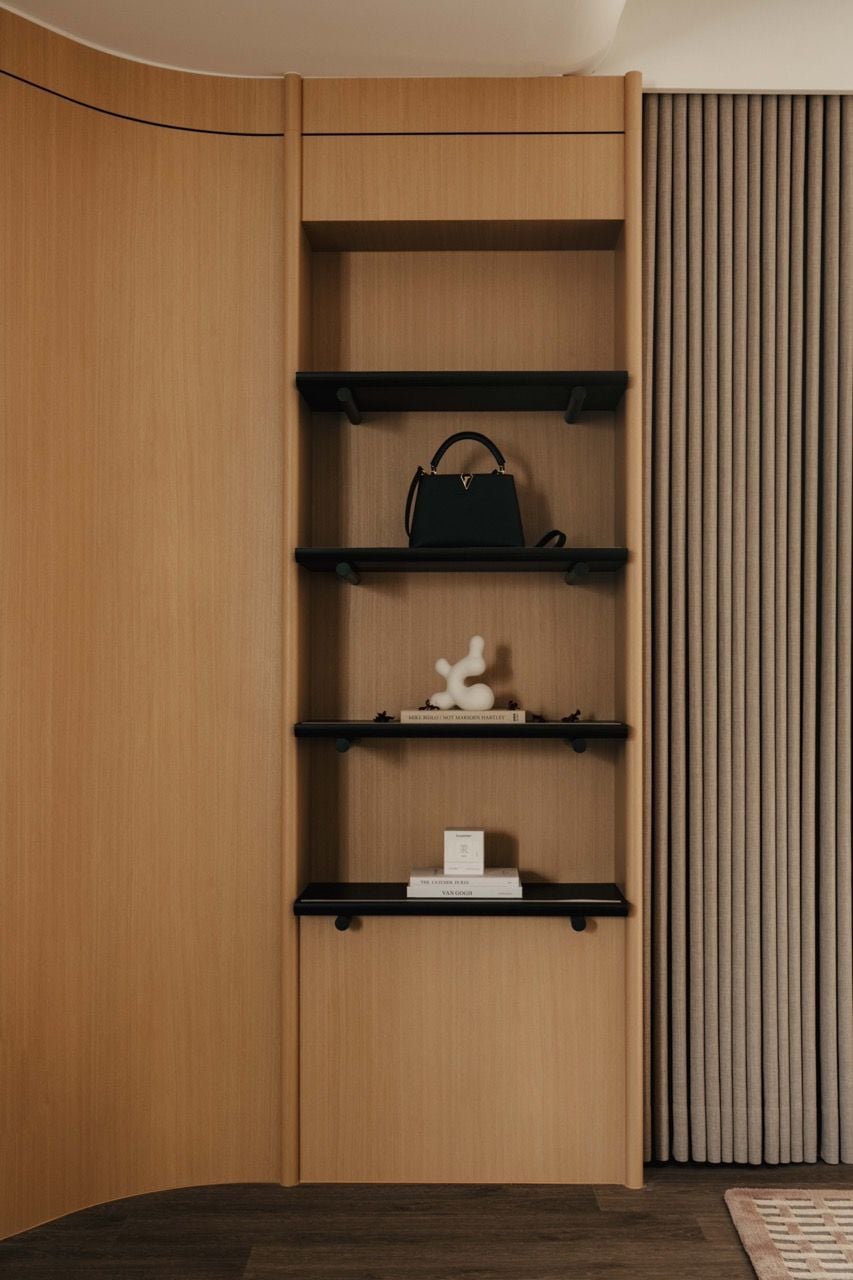 Built-in natural veneer shelving with curved elements, showcasing the custom joinery work and the warm wood tones used in the interior design