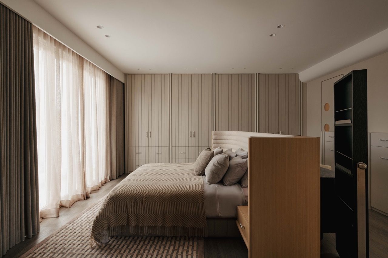 The bedroom features floor-to-ceiling natural veneer storage and demonstrates the tone-on-tone palette that creates a cosy atmosphere