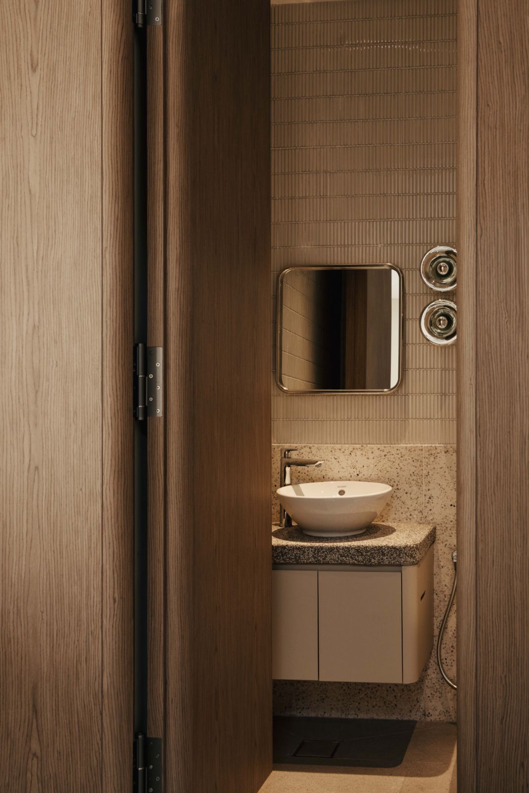 Powder room with natural veneer cabinetry and stone surfaces, showing how the material consistency extends to all areas of the house