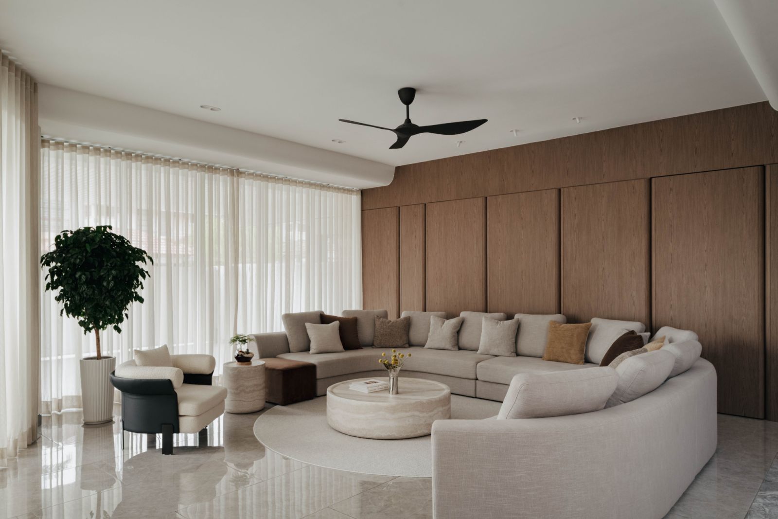 Living room showing the sectional sofa arrangement and natural veneer wall treatment, with abundant natural light from the reconfigured window placement