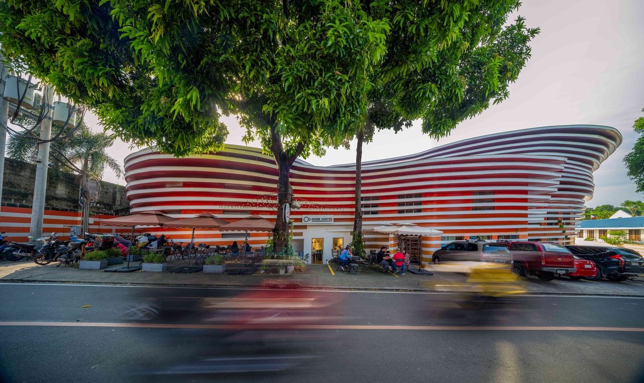 The warehouse's curved design was influenced by the road's shape and adapted to neighbouring structures, while also preserving an existing Mango tree at the front