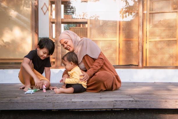 Happy Asian muslim mother playing outside with her son and daughter