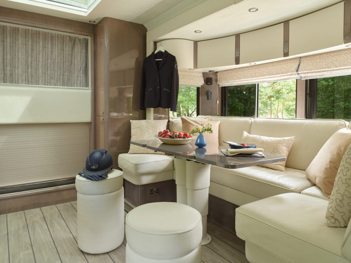 White buffalo leather seating and soft grey quarter-cut ash veneer create a refined living space in the horsebox that feels more like a private club than mobile accommodation