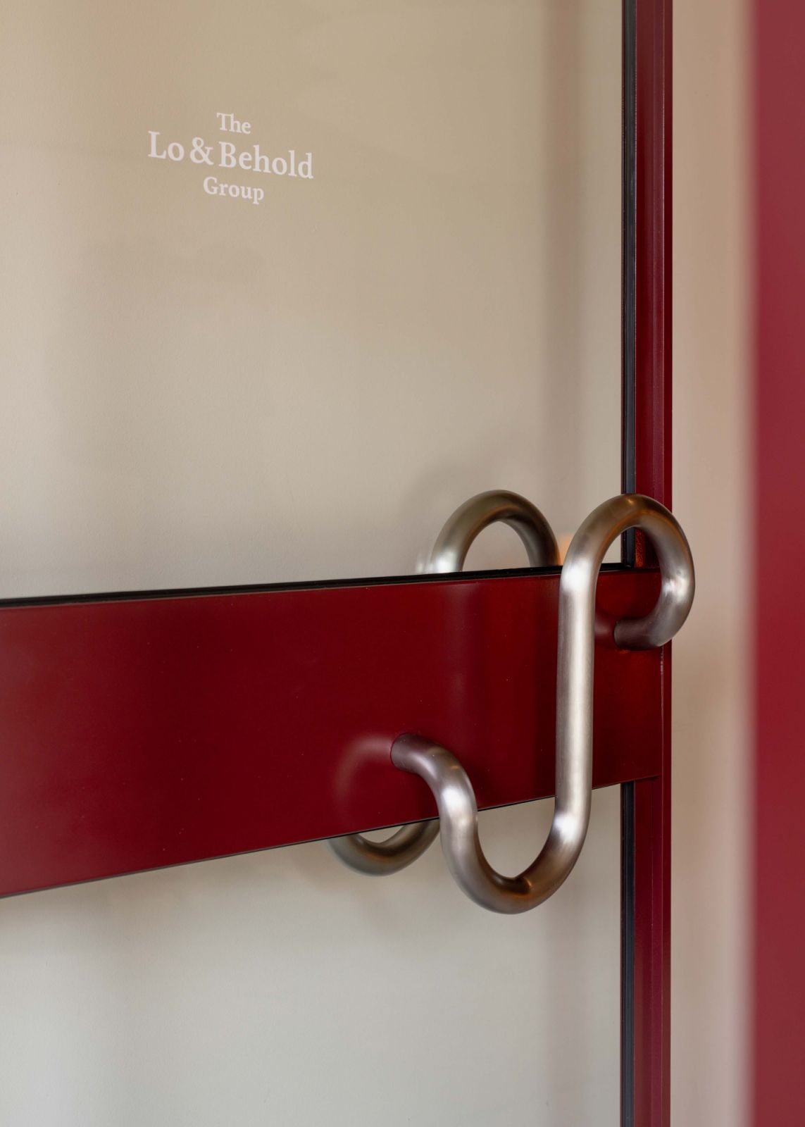 Close-up of the entrance door handle, which takes its shape from the ampersand from the Lo & Behold Group’s logotype