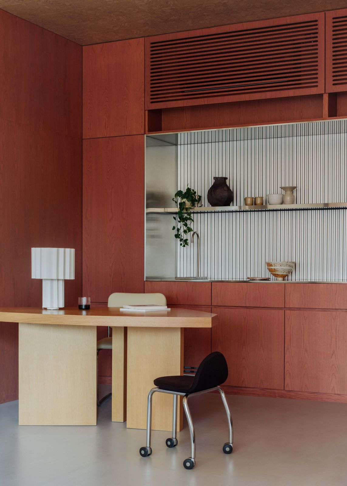 The reception area, backed by burnt red-stained timber joinery and corrugated metal details, with a custom-designed reception desk