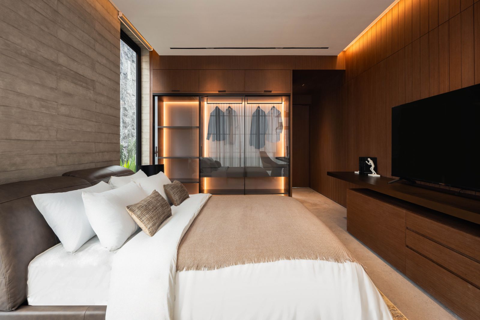 The red-tinged timber finish of this bedroom gives it a distinctly Southeast Asian vibe