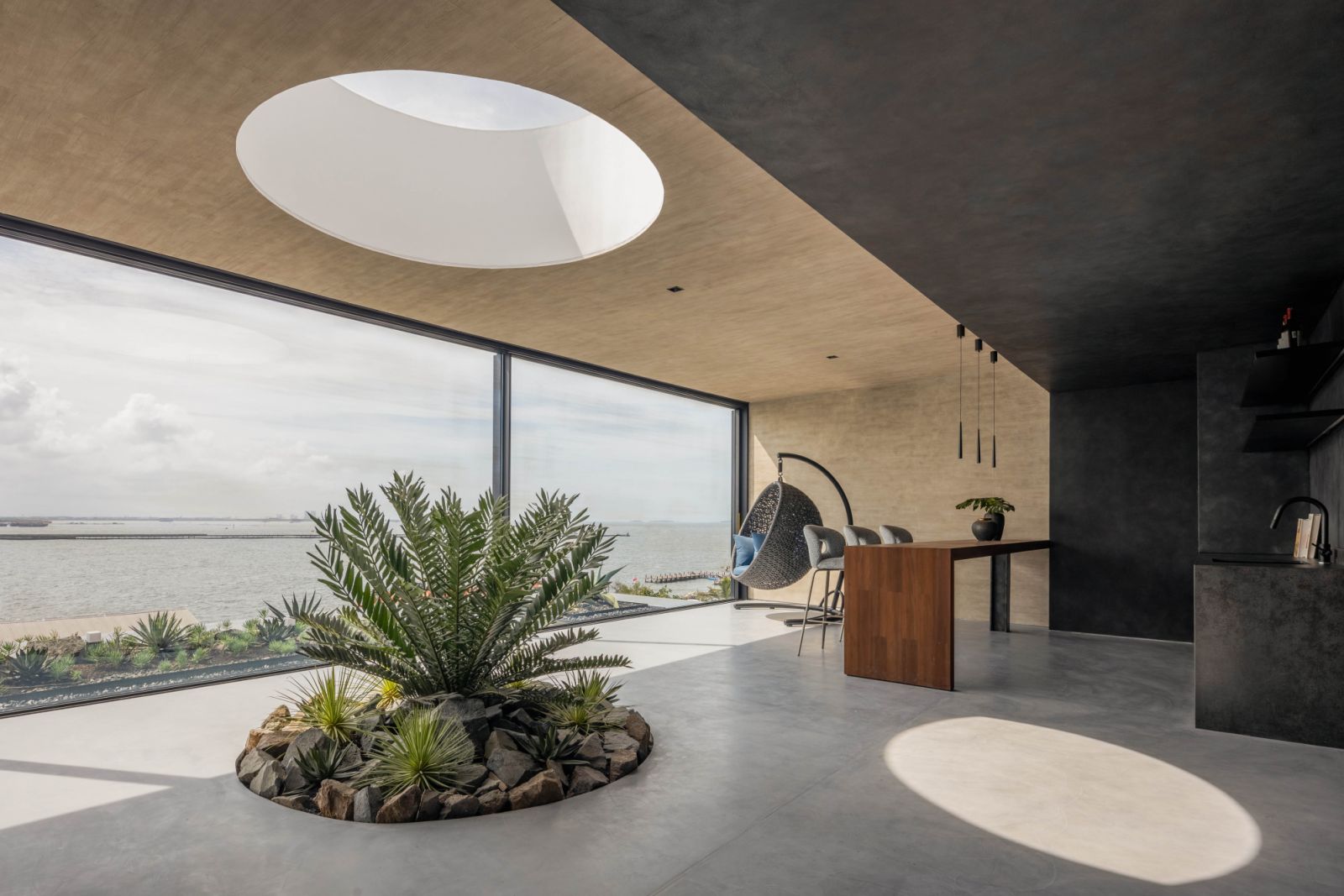 A circular cut-out above a mini garden lets the sunlight and rain through