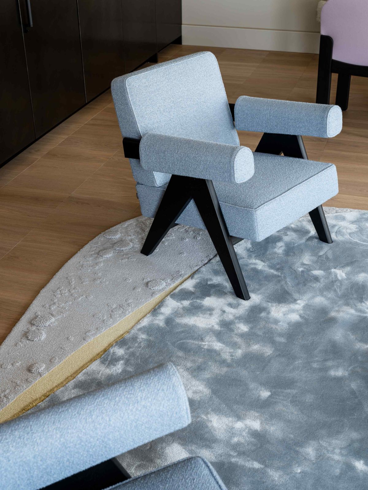 A pair of Pierre Jeanneret’s Capitol Complex armchairs in light-textured fabric offer visual balance and additional seating
