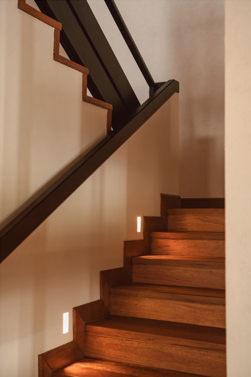 Stair detail with integrated lighting, demonstrating how the renovation embraced the original structure’s beams rather than concealing them