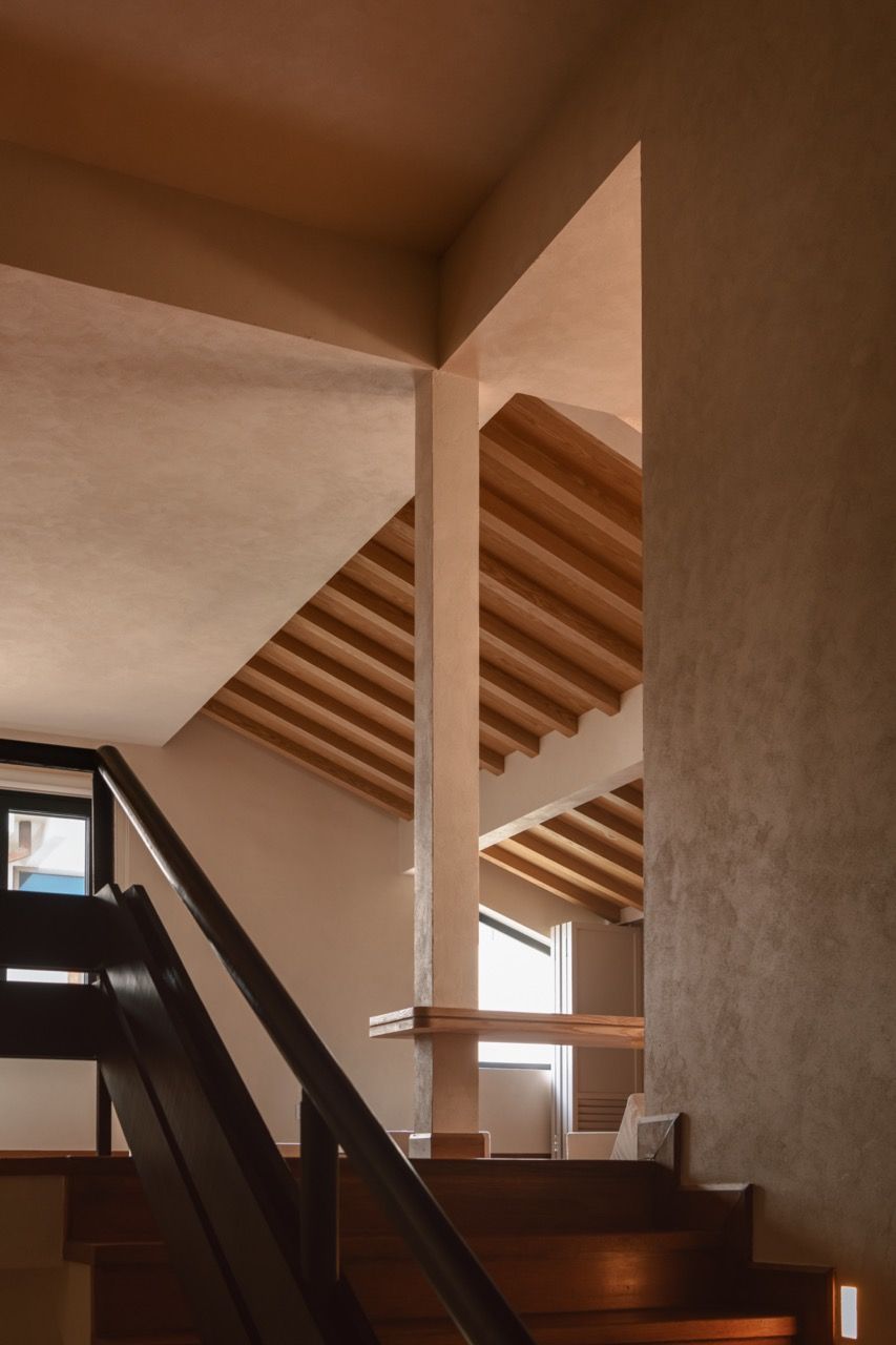 The staircase area showcasing the low ceiling beams and textured Murobond paint finish applied by hand throughout the house, creating depth and character