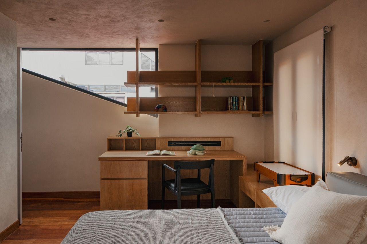 The master bedroom features the Senply timber veneer in its natural tone, accompanied by custom-built-in storage and a desk area. The low ceiling beams that were once considered problematic now add character to the space.