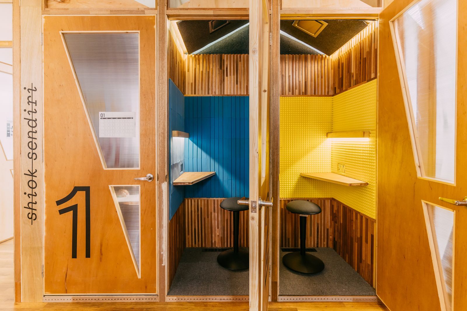 Colourful private work pods with custom timber construction and bright acoustic panels, demonstrating how the studio creates intimate focus spaces within the larger collaborative environment