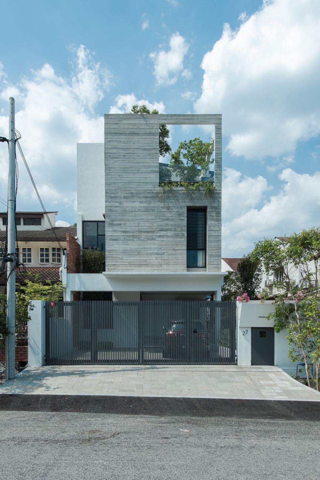 Contemporary residential facade featuring board-marked concrete and strategic window placement, demonstrating EJA’s approach to modern urban housing that responds to the tropical climate while maintaining privacy through vertical screening elements