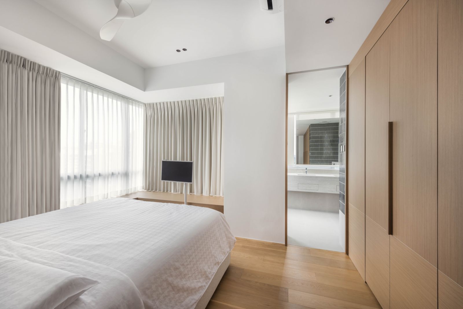 Pale wood, off-white walls and diaphanous curtains lend a sense of lightness to the serene master bedroom, which also benefits from the abundance of natural light which infuses it with a breezy aura