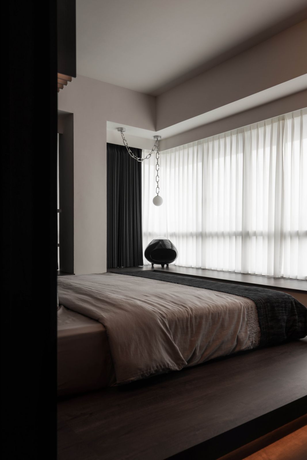 The same pendant light coexists harmoniously with a sculptural cat bed placed atop the bay windowsill