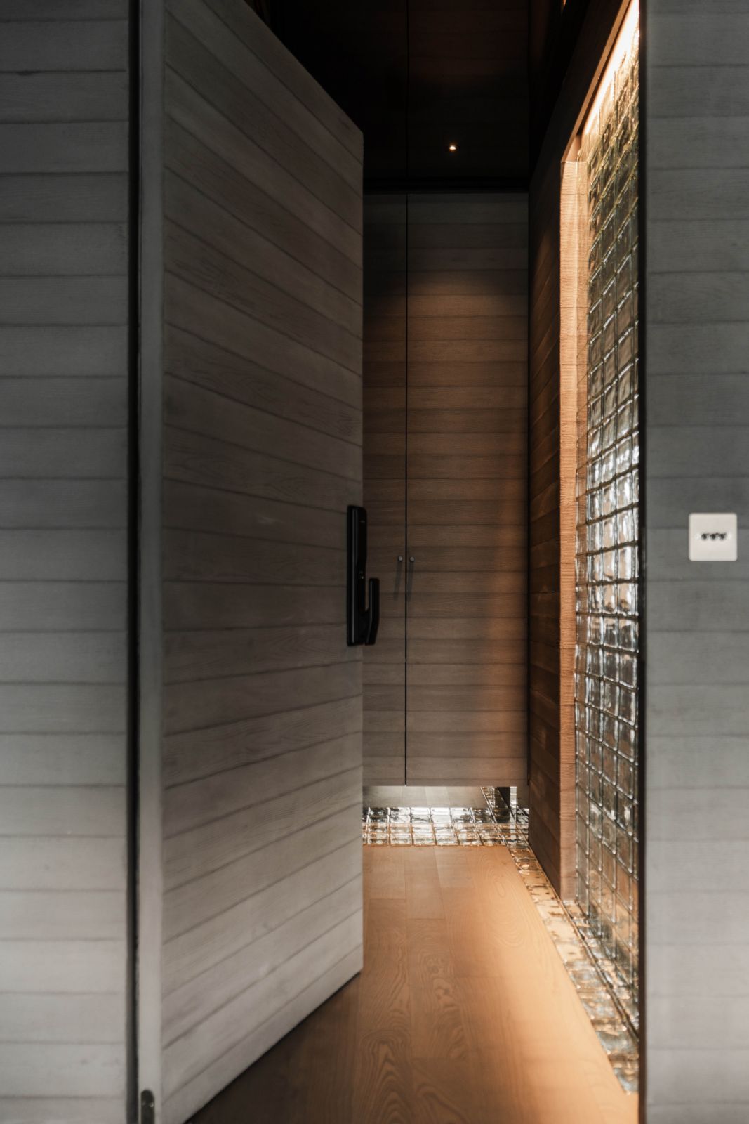 Glass bricks meet greige-toned timber in the entrance