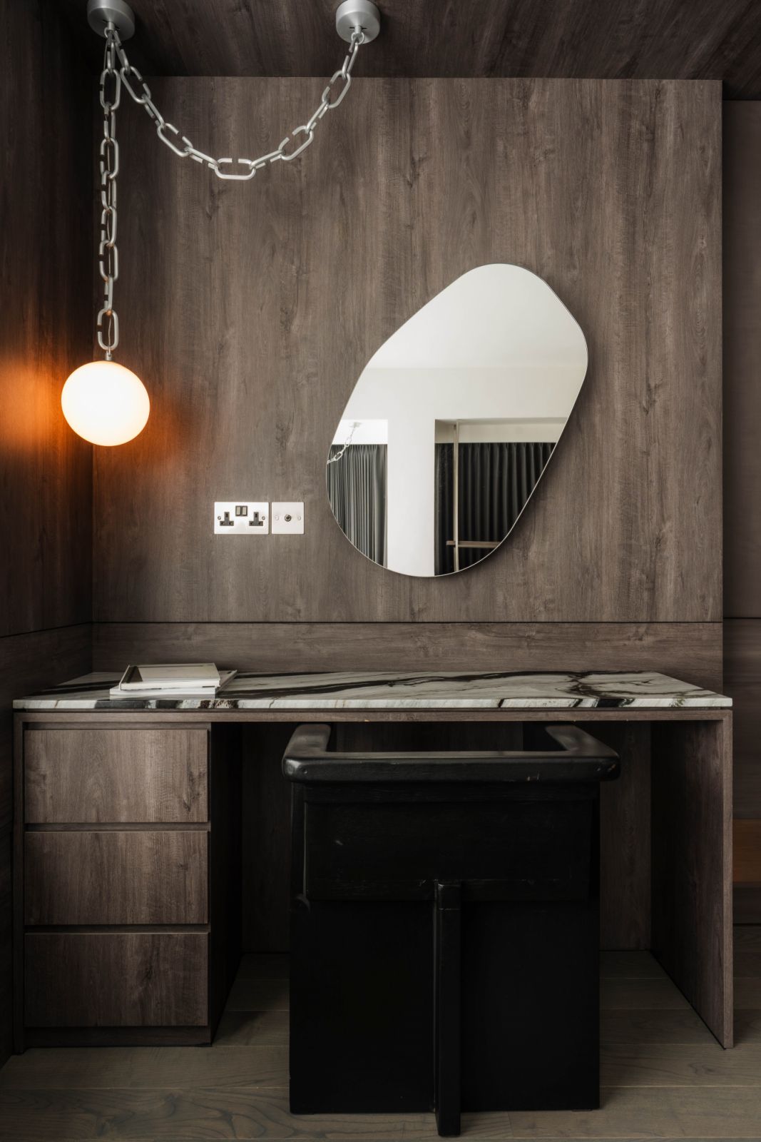 An organic-shaped mirror, Boba Chain pendant and marble tabletop bring a sleek, contemporary edge to the study corner