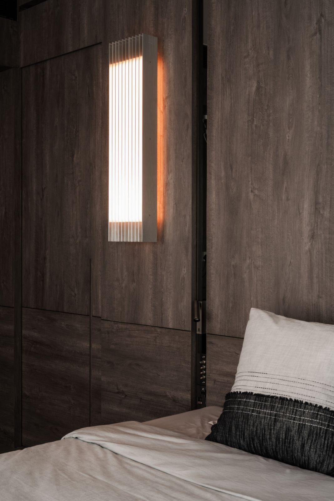 Tsai’s Grid light is mounted on a dark-veneer wall