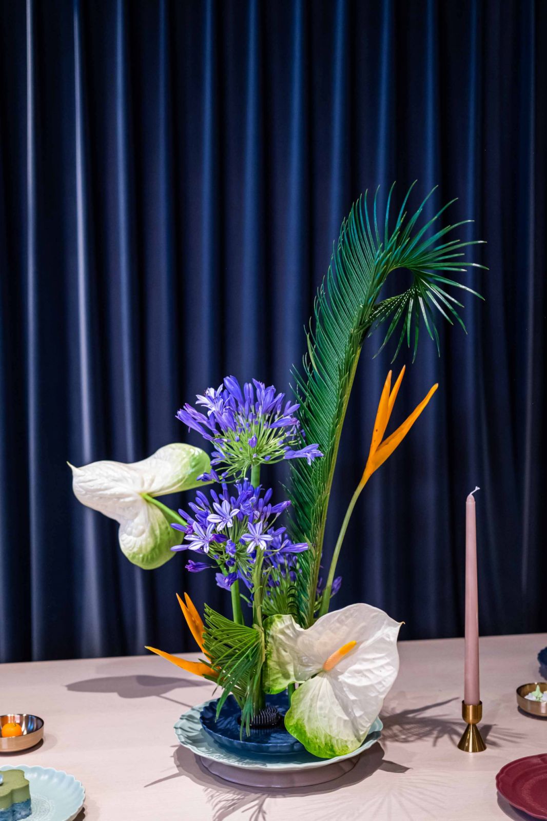 A sculptural floral arrangement by Fiore Dorato and curtain backdrop by Coesa complement the tablescape by Luzerne