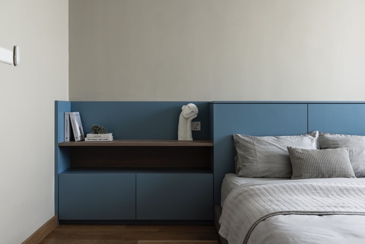 A built-in blue headboard incorporates bedside storage and lighting, creating a calm focal point