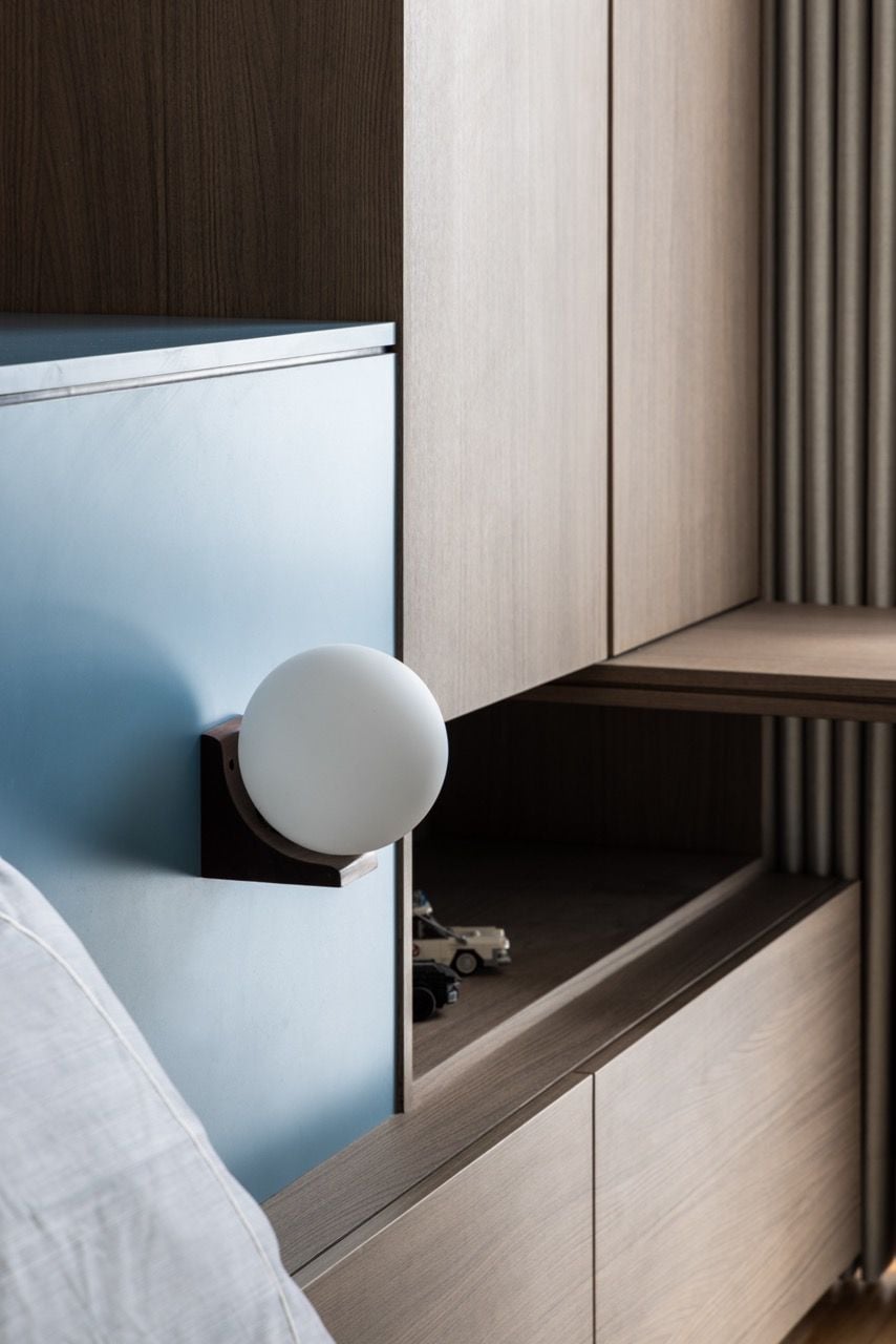 Fluted wood panelling and a minimalist white sconce demonstrate the apartment's attention to tactile textures