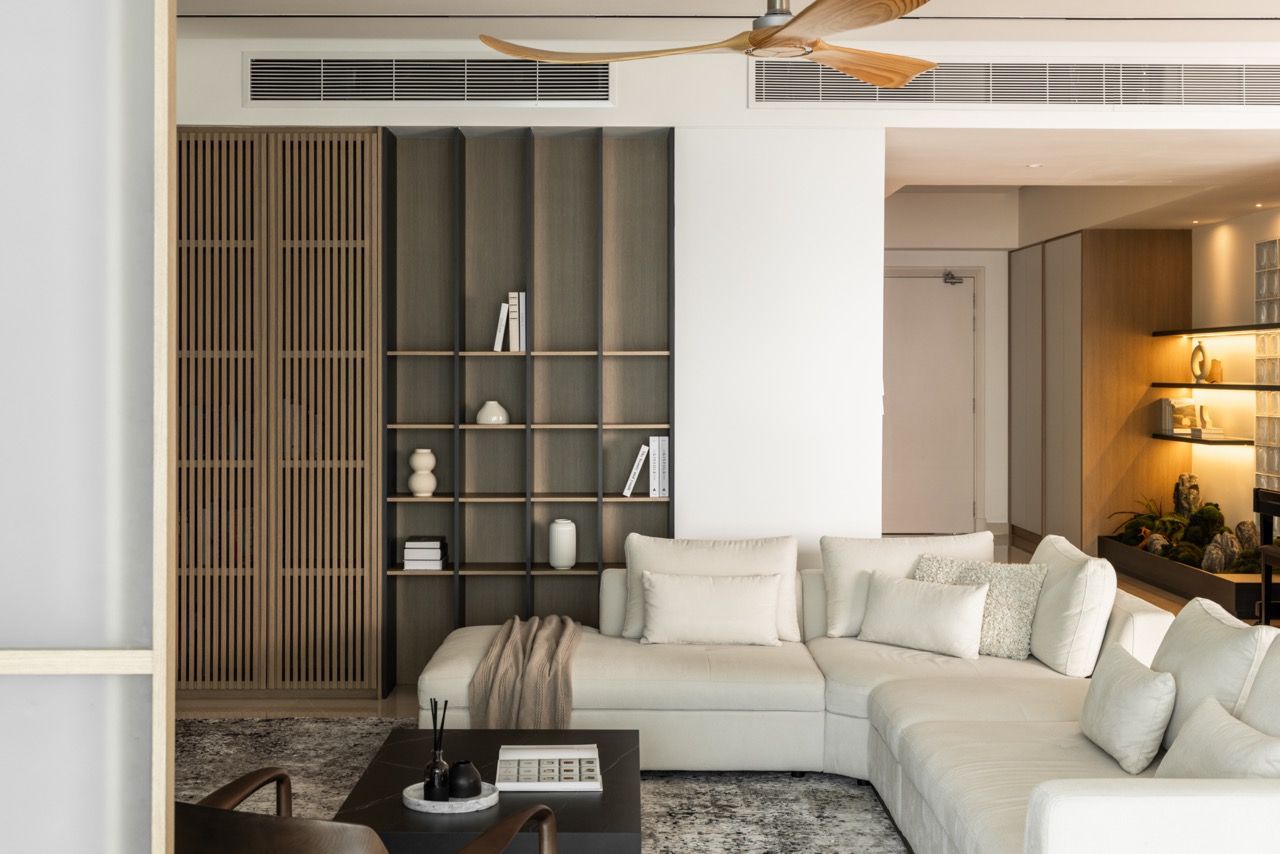 The full-height shelving wall anchors the seating area while allowing views through to other spaces