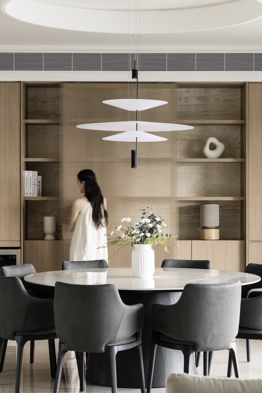 The open shelving displays ceramics and books with gallery-like precision, while the dining setup shows how the space accommodates daily life