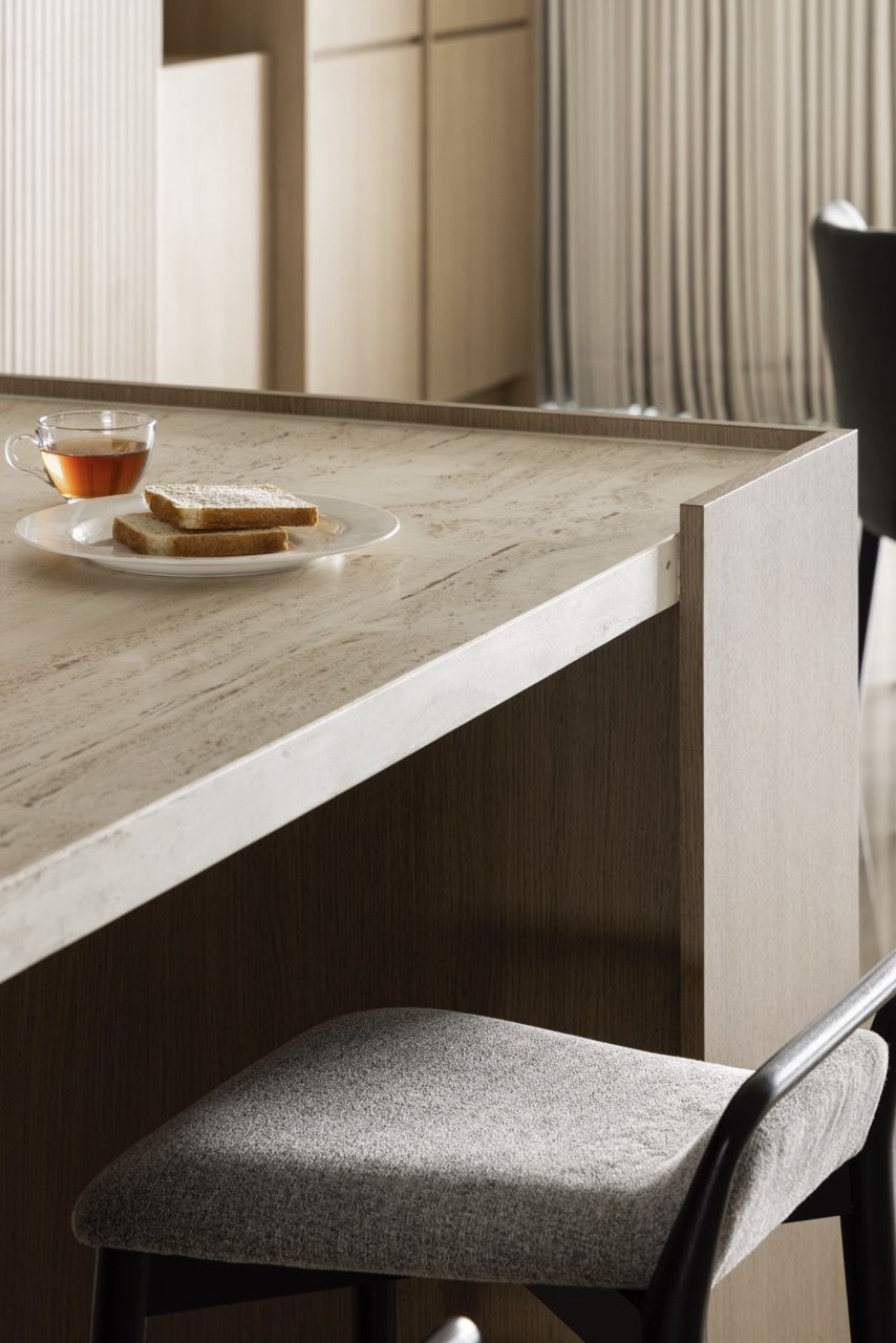 Cane-fronted lower cabinets and travertine backsplash show the layering of natural textures.