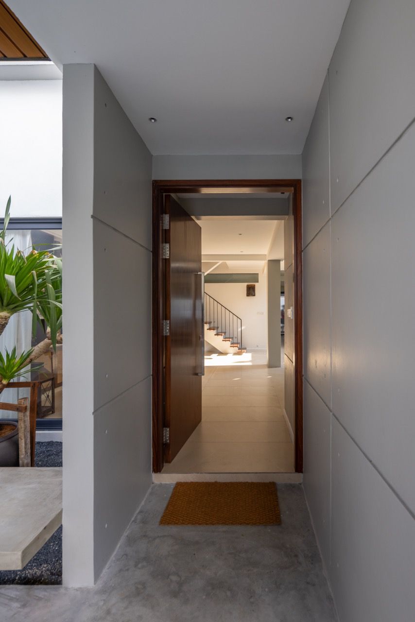 The entrance hall leads through custom-designed timber doors into the extended ground floor, where natural light filters through the double-height void created by removing part of the first-floor slab