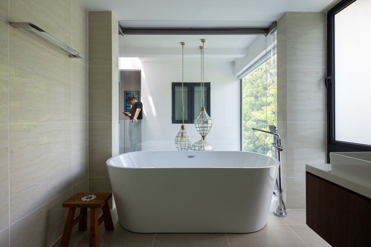 The master bathroom features a freestanding bathtub with garden views, using the natural light advantages of the end-lot position, whilst aluminium louvres provide privacy and filter harsh afternoon sun