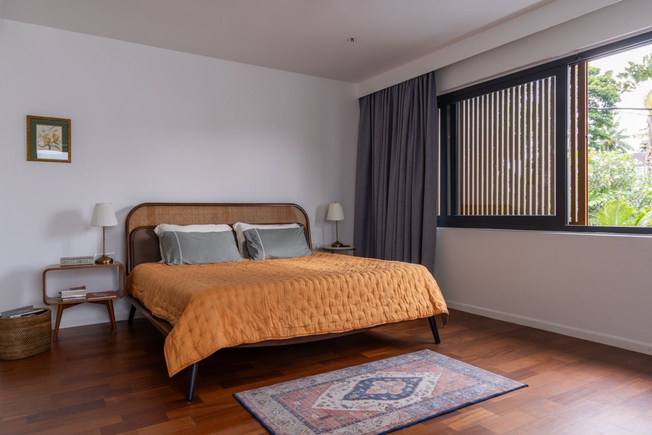 The master bedroom showcases timber flooring and features aluminium louvres that provide privacy whilst filtering the afternoon sun