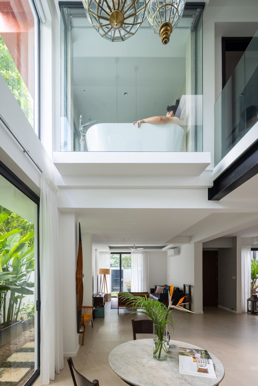 The transparent bathtub suspended in the double-height void exemplifies the nomadic voyeurism concept borrowed from Neri & Hu architects, creating an unexpected focal point visible from the living areas below