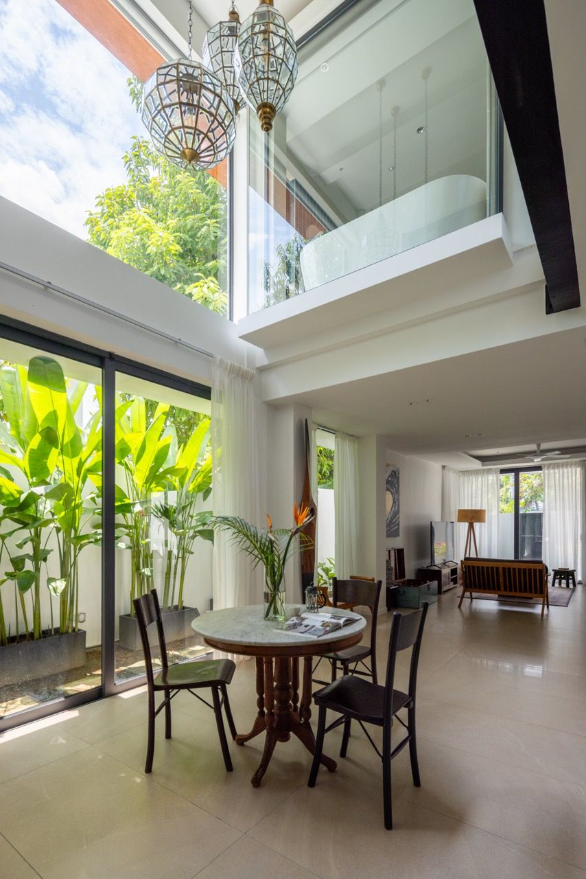 The double-height living space demonstrates how removing part of the first-floor slab created dramatic vertical volume, with the suspended bathtub visible above and natural light filtering through multiple levels.