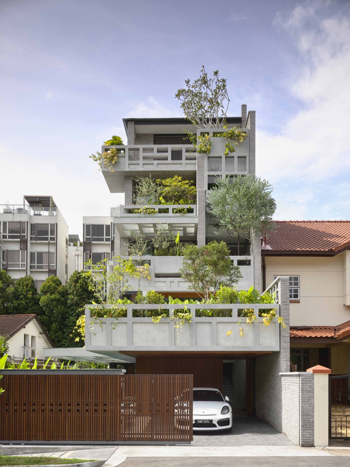 The semi-detached house blends lush greenery with a concrete architectural shell
