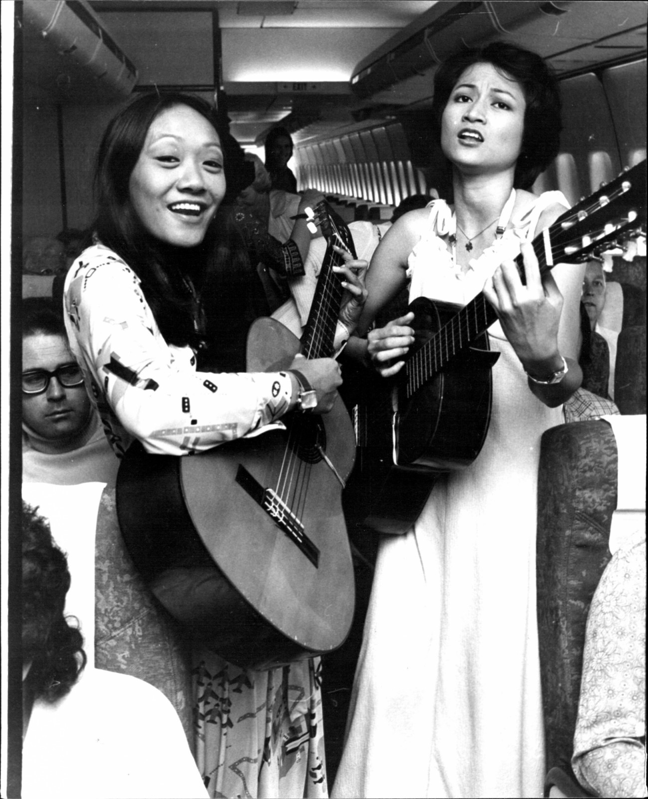 Singapore Airlines have introduced live entertainment on their Sydney - Singapore flights, the first airline to do so. The entertainers are Ning Sotto and Inch Gaddi from the Philippines who play guitar and sing. The girls perform on two flights a week, playing and singing just after take-off, at lunch and prior to landing in Singapore. Here the girls Ning Sotto (left) and Inch Gaddi (right) are shown singing to passengers on a 747 Jumbo at Mascot Airport. May 21, 1976. (Photo by Anthony Matthews Lensen/Fai