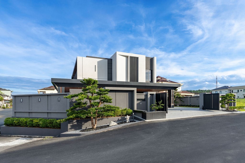 The villa's contemporary facade in Bidor, Perak, demonstrates the clean lines and material palette of natural stone, matte finishes, and eco-certified wood that define the project