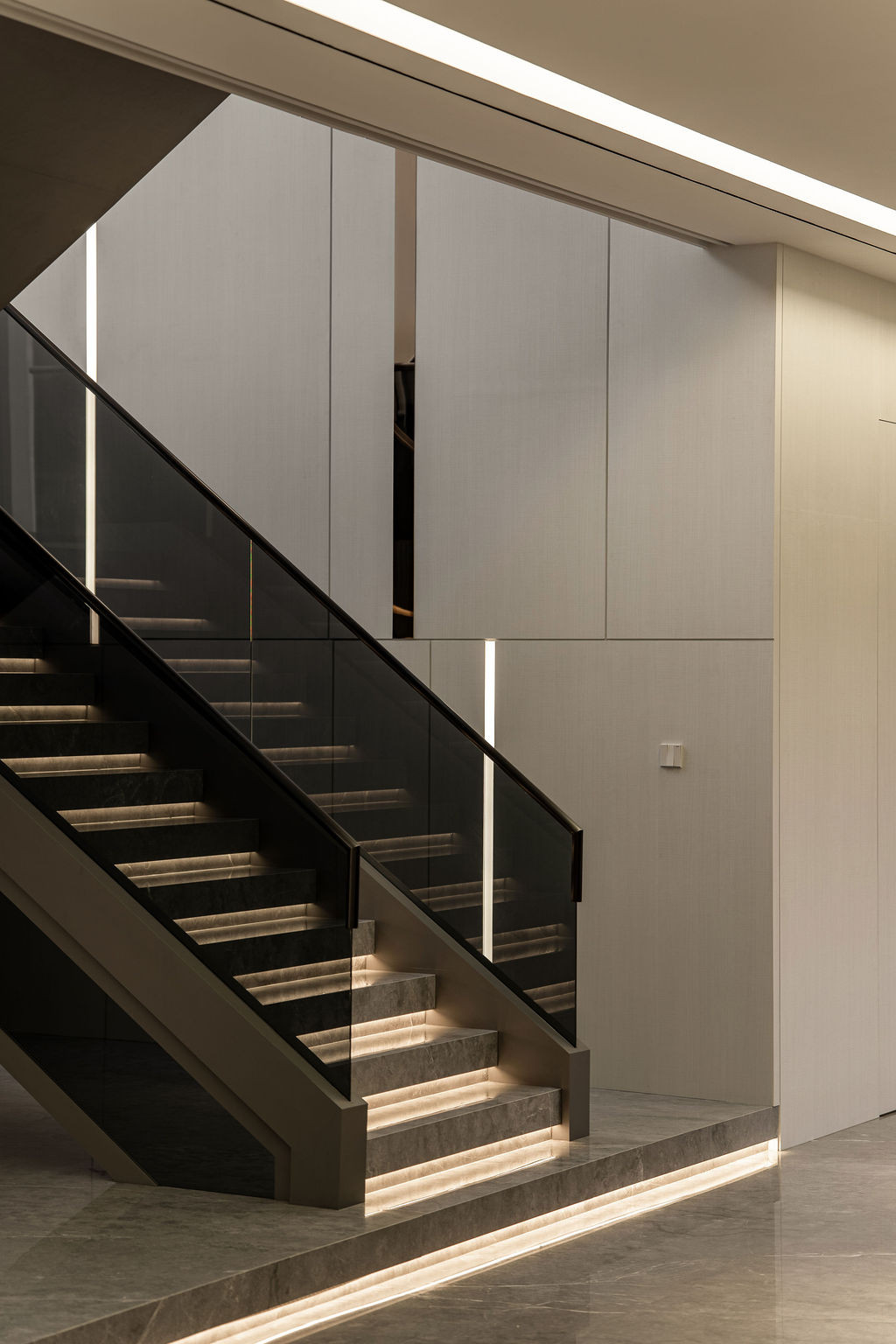 The main staircase with integrated lighting demonstrates the precision in material transitions that required extensive coordination with local contractors unfamiliar with the design team’s detailing standards