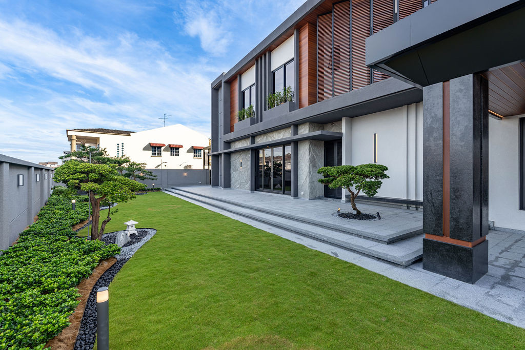 The landscaped garden and covered walkway showcase outdoor circulation, with the villa’s facade displaying the weather-resistant materials chosen for Malaysia’s demanding climate