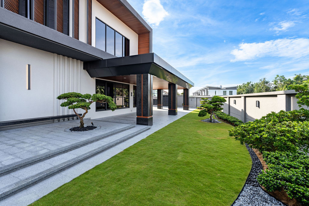 The garden and covered walkway show the outdoor circulation, with mature landscaping complementing the villa's material palette of stone and wood